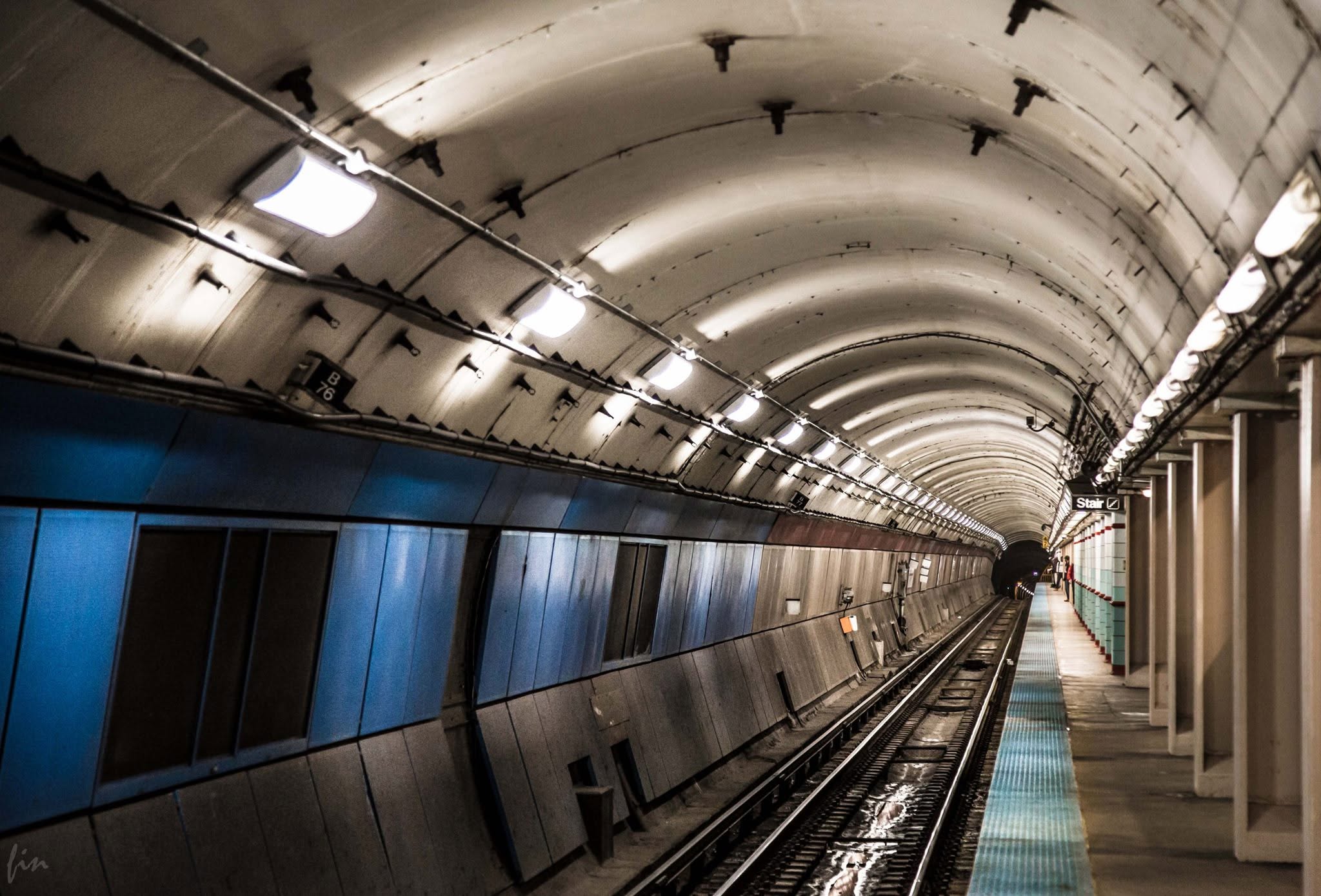 Chicago subway tracks curving through a silver and blue tunnel.